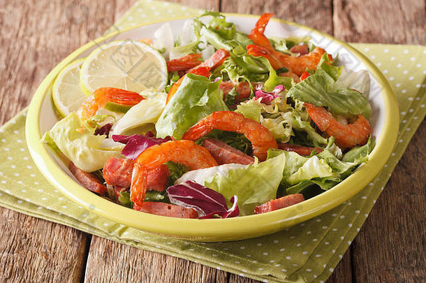 的沙拉，<strong>虾</strong>，香肠，酸橙和混合的绿色特写镜头放在桌子上的盘子上。水平的