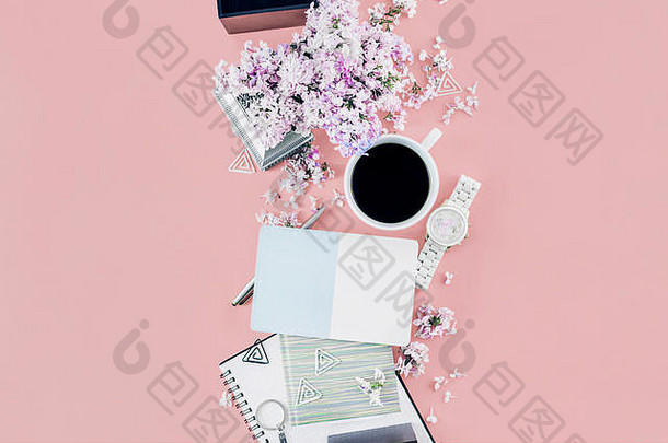 妇女工作场所概念。粉色背景上的卡片、咖啡杯、鲜花和个人配件，平面俯视图