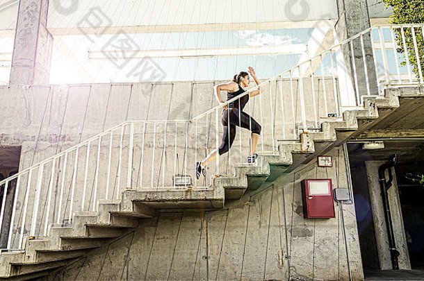 穿着黑色运动服的跑步女子，跑上楼梯