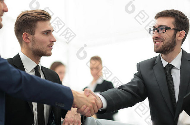 合作伙伴在团队成员面前完成交易并握手