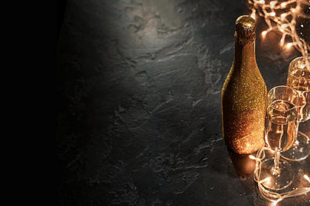 金色香槟酒瓶，两个酒杯，黑色背景上燃烧的花环
