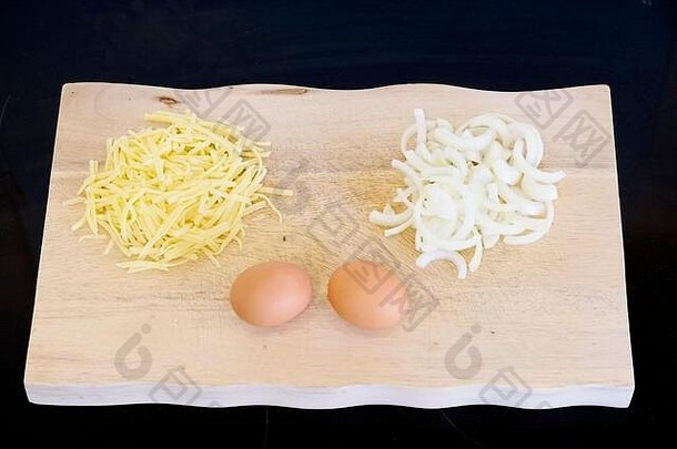 木制砧板上的洋葱、奶酪和鸡蛋