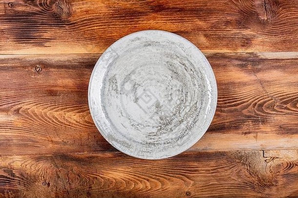 木桌上的白色盘子。旧木制背景上的空盘子。俯视图