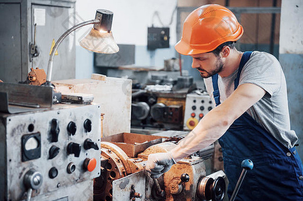 一个戴着安全帽的年轻工人在一家大型金属厂的肖像。工程师为机器提供服务，并为气体设备制造零件