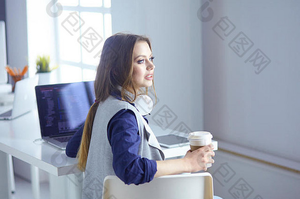 戴着耳机的专注专注的女人坐在桌旁，拿着笔记本电脑，看着屏幕，做笔记，在互联网上学习<strong>外语</strong>