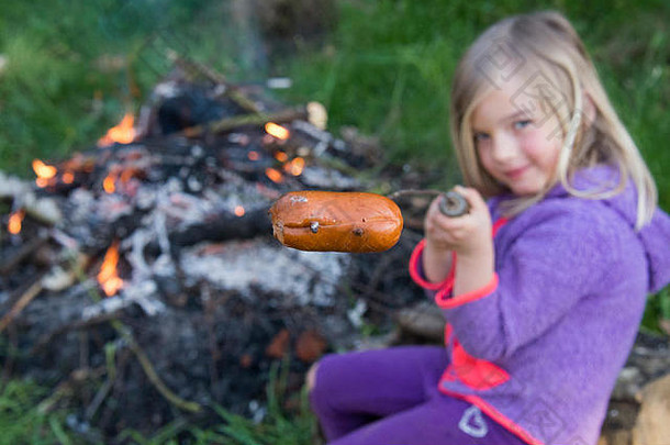女孩准备吃香肠煮熟的营火