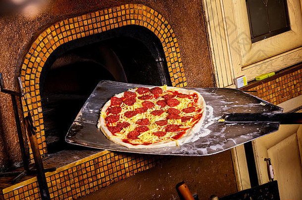新鲜的意大利<strong>原汁原味</strong>比萨饼放在铁锹上，放入传统的木烧石烤箱中。