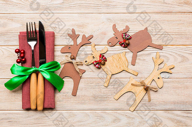 餐巾纸上新年用具的俯视图，带有节日装饰和木制背景上的驯鹿。圣诞晚餐概念的特写镜头。