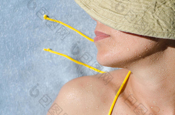 特写镜头：一名妇女脸上滴着水滴进行日光浴。