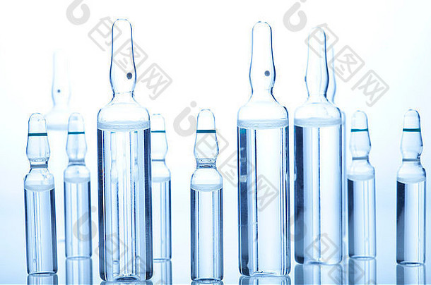 白色和蓝色背景上带有液体的玻璃药瓶