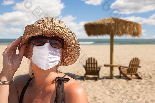 沙滩上戴着口罩的度假妇女。。