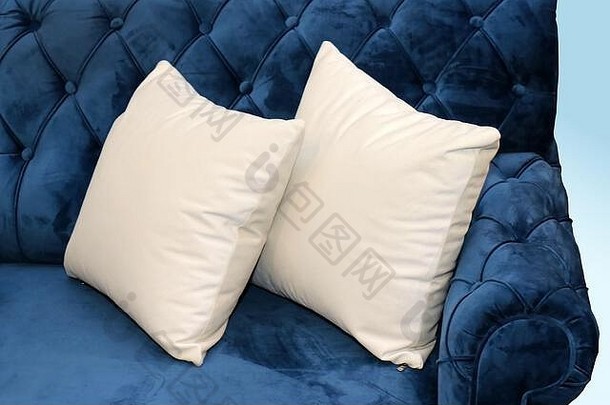 复古蓝色沙发角落的两个白色纺织枕头