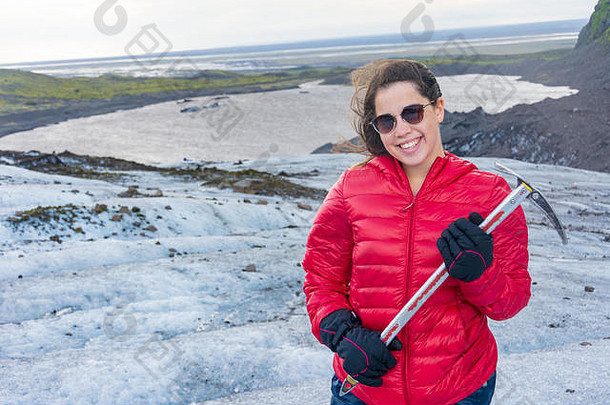 在冰岛南部令人惊叹的瓦特纳乔库尔冰川上，一名年轻女子手持冰斧进行蓝色冰之旅