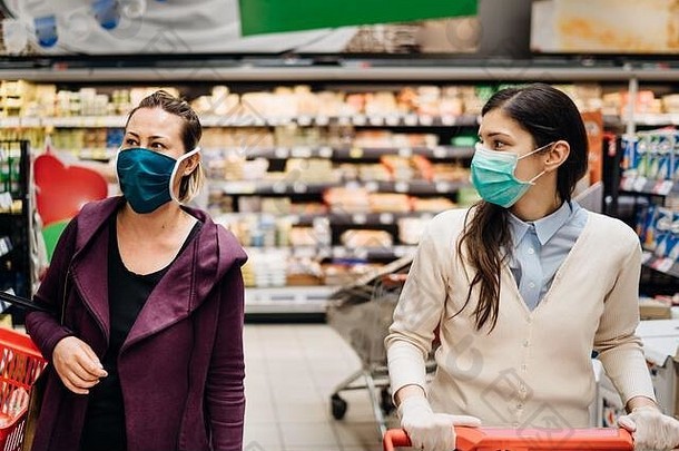 在杂货店，由于冠状病毒大流行，带着口罩的购物者正在购买食品。2019冠状病毒疾病。检疫准备。抢购和抢购