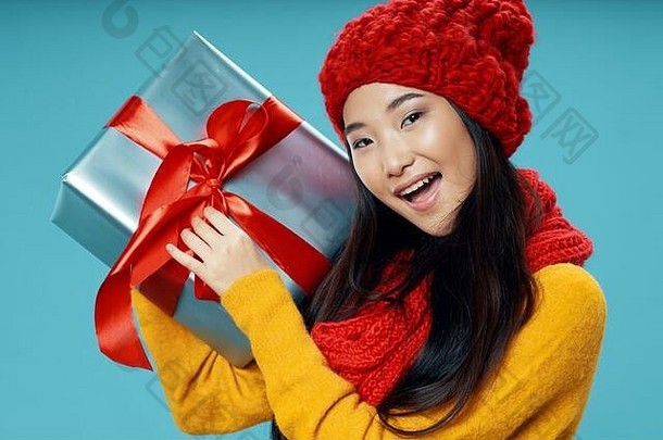 快乐的女人在脸旁拿着一个装有礼物的盒子