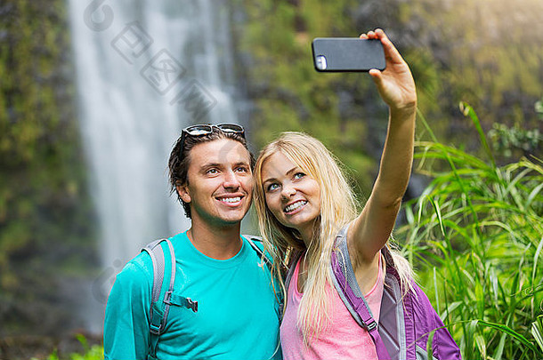 一对夫妇在户外玩得很开心。徒步前往夏威夷不可思议的瀑布后，用照相手机拍摄自画像。
