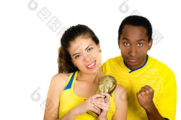 迷人的跨种族夫妇穿着黄色足球衫，<strong>手持</strong>小奖杯摆出<strong>拍照</strong>姿势，白色工作室背景