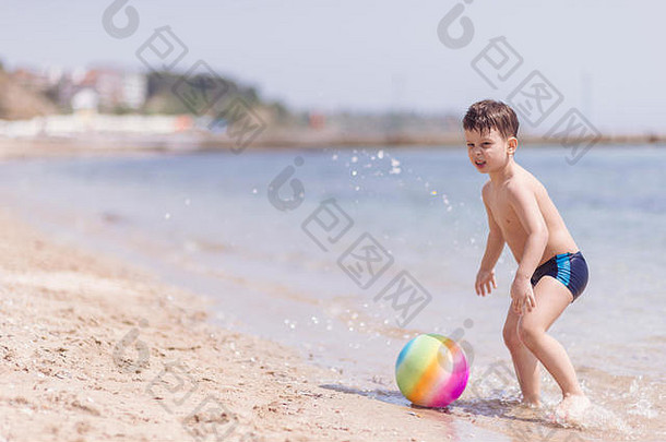 可爱的男孩站水海滩玩色彩斑斓的球有趣的