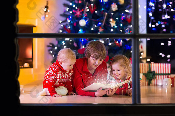 平安夜，孩子们在壁炉边看书，打开礼物。一家人带着孩子庆祝圣诞节。装饰客厅