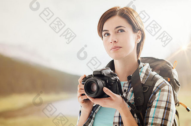 年轻的女摄影师徒步旅行山拍摄相机微笑