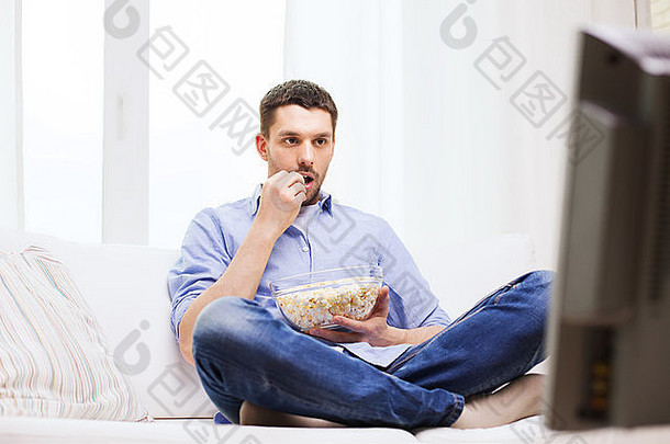 男人在家看电视和吃爆米花