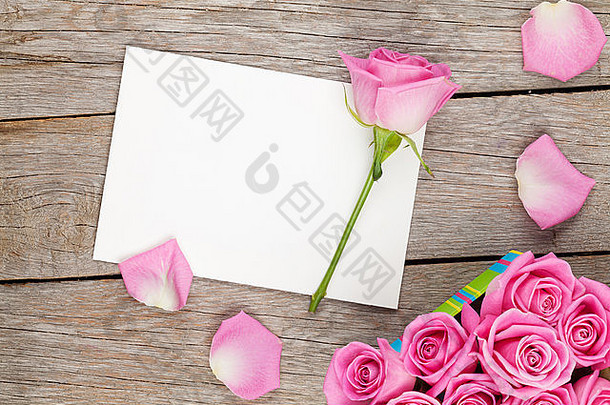 情人节贺卡或相框和礼品盒，木质桌上放满粉红色玫瑰。俯视图