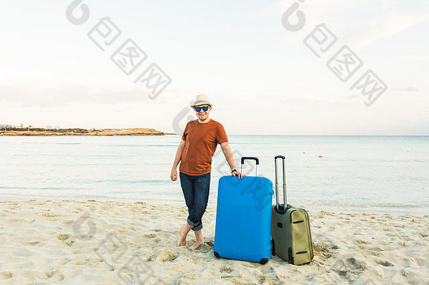 海滩上拿着手提箱的男人。<strong>暑期旅游</strong>与度假理念