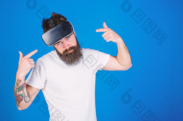 留着时髦胡须的男人在蓝色背景上为新玩意儿做广告。时髦时尚，造型酷炫，时尚胡须直指VR heaset。胡子纹身男人享受3D体验，虚拟现实概念。