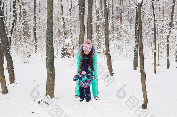 快乐的家庭母亲和小女孩在冬天的户外雪中嬉笑