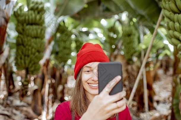 女人旅游穿着红色的探索香蕉种植园拍摄视频博客电话概念健康的吃绿色旅游