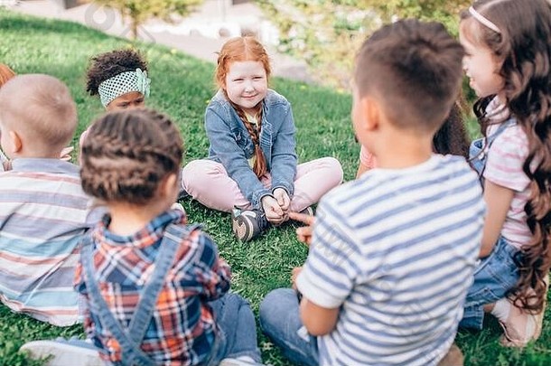 友谊、童年、休闲和人的概念——一群快乐的孩子或朋友坐在夏季公园的草地上