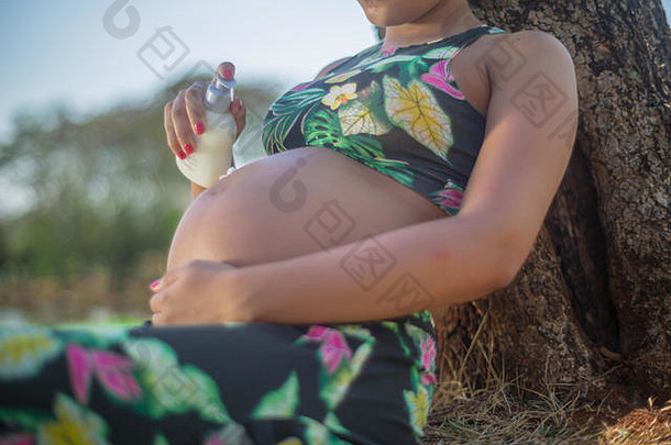公园里的孕妇在腹部涂上乳霜以避免妊娠纹。