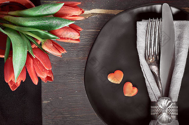 春天菜单概念黑色的盘子黑色的餐巾古董餐具红色的郁金香装饰心