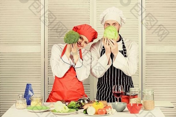 夫妻俩正在做健康的素食。素食家庭。素食营养和蔬菜饮食。他们心里想着饮食。一对厨师把卷心菜和花椰菜放在脸前。健康食品概念。
