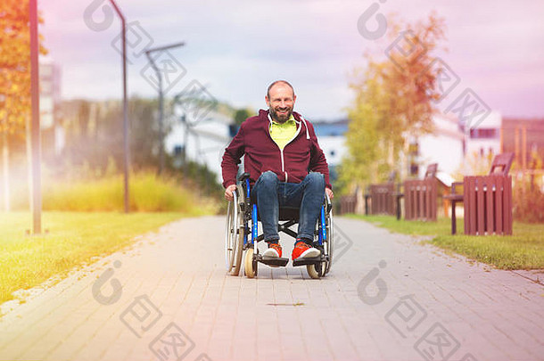 快乐微笑的残疾人坐在公园的轮椅上