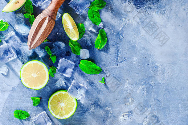 夏季饮料头，含莫吉托鸡尾酒成分、薄荷、酸橙和冰块。灰色石头背景上的柠檬铰刀或榨汁机，带有复印空间。