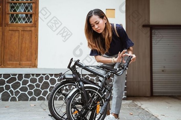亚洲年轻的女人褶皱折叠自行车准备工作前面房子