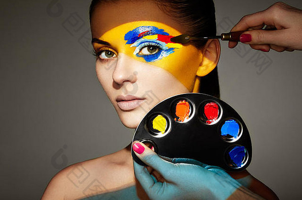 化妆师用五颜六色的化妆品。画着彩色脸的时装模特。美丽模特的美丽艺术肖像，彩色抽象画