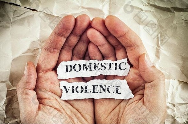 家庭暴力。一名妇女手里拿着撕碎的纸，纸上写着“家庭暴力”字样。概念形象。特写镜头。