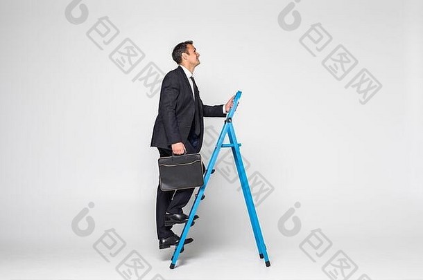 一个商人爬上梯子的侧视图，在白色背景上被隔离。