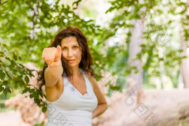 丰满的中年女人穿着白色长棕色（的）波浪头发指出手指手查看器相机