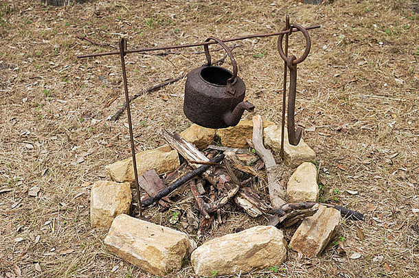 农村外一处未点燃的明火上，铁架上的生锈的旧水壶
