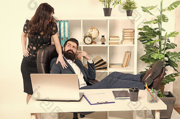 提供按摩服务。留着大胡子的时髦老板坐在办公室内部的皮扶手椅上。工作场所的老板和女秘书。工作关系。商务人员和员工的概念。懒惰的老板办公室。