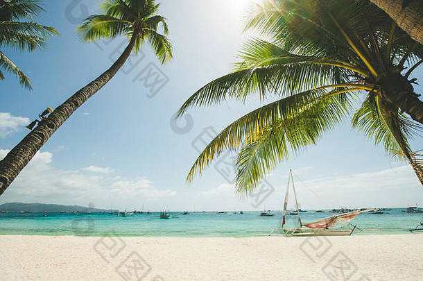 菲律宾长滩岛完美的白色沙滩。椰子树映衬蓝天，船在大海。晴朗的天气。旅行背景。自然景观。异国情调岛屿度假休闲酒店
