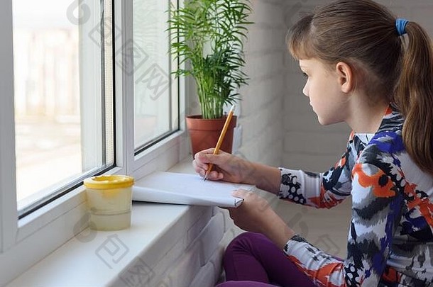女孩在窗台上用铅笔画册