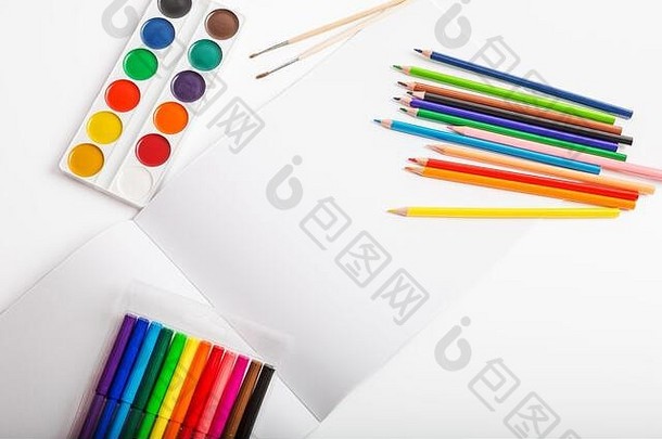 画册和学习用品-彩色铅笔、毛毡笔、水彩颜料和画笔在白色背景上的特写，文本空间