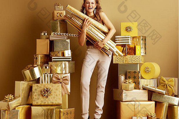完整的长度肖像时尚的时尚迷黄金米色裤子棕色（的）上衣黄金包装纸卷桩金礼物