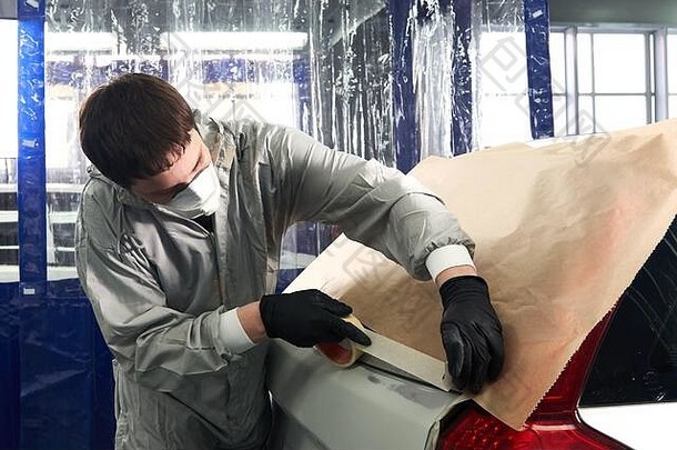 在汽车维修服务中，在喷漆前用纸覆盖汽车的机械师