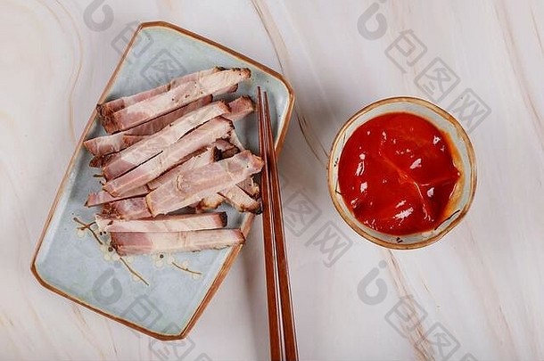 亚洲肉片，用辣酱和筷子放在盘子上。