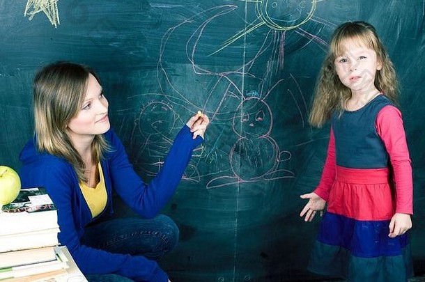 年轻的老师带着小gitl<strong>小学生</strong>在黑板上画画，自学妈妈带着女儿一起在<strong>自我</strong>隔离、生活方式上做人的理念